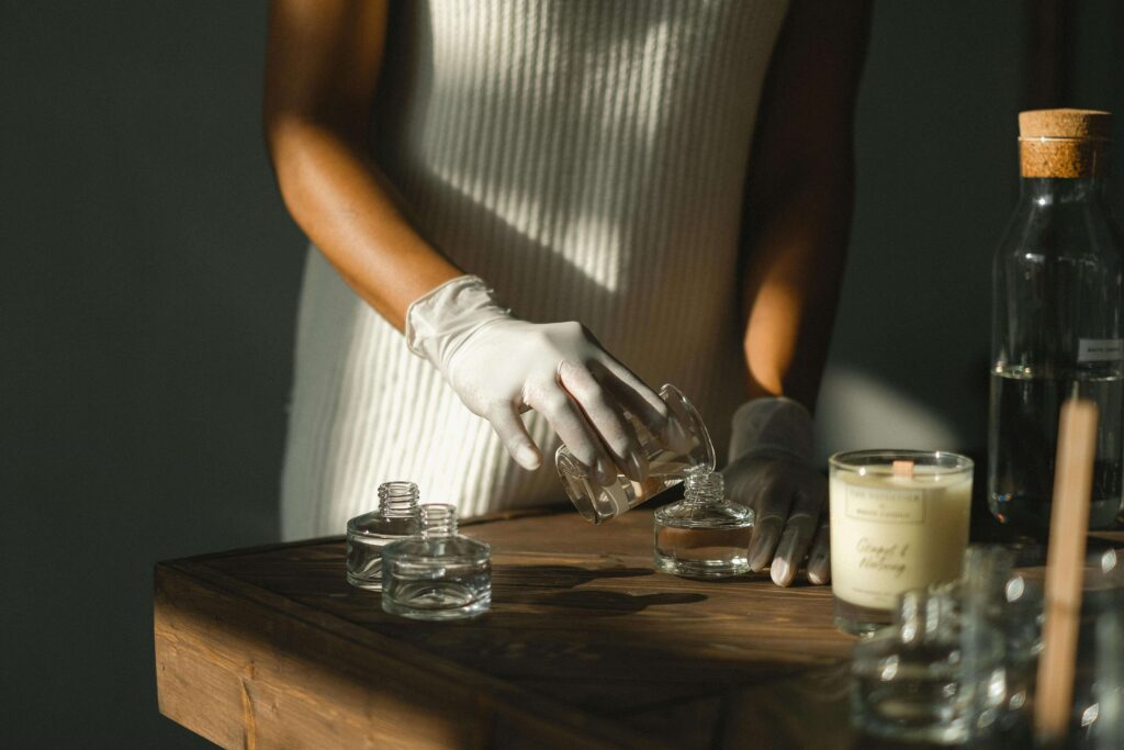 Une femme en train de verser sa création aromatique dans des flacons transparents