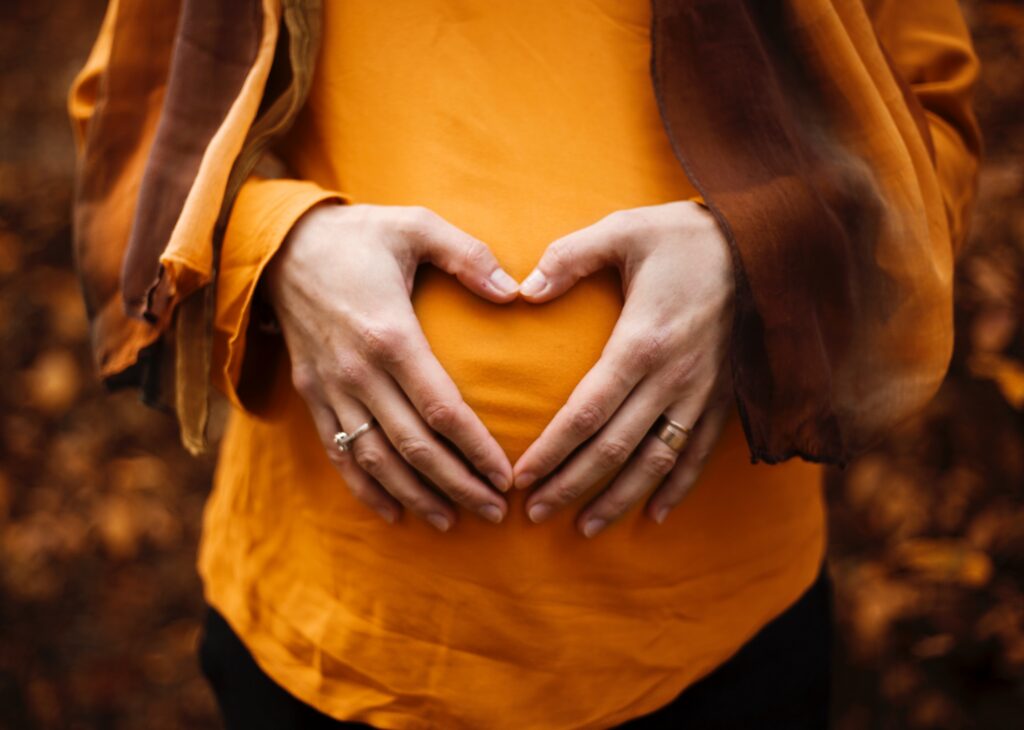 Gros plan sur une femme enceinte qui fait un geste de coeur avec ses mains